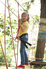 Wall Mural - Little girl climbing in adventure park. Summer camp