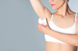 Woman doing armpit epilation procedure on grey background, closeup. Space for text