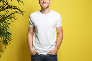 Young man wearing blank t-shirt on yellow background, closeup. Mockup for design