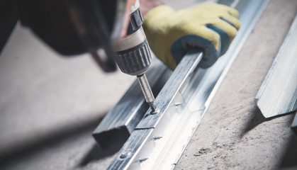 Worker twists the screw into the metal.