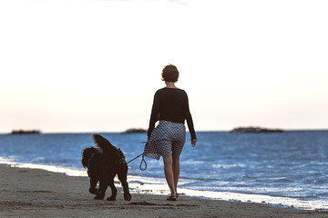 Woman with her big inseparable dog walking by the sea