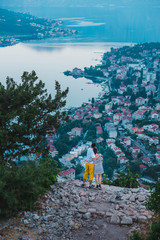 Couple stands on the cliff and looking on the Boka Kotorska Bay view. Travellers on the Kotor landscape background