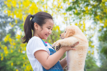 Young asian girl holding a little golden retriever dog in park