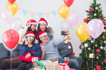 Wall Mural - Young asian people ,a man and three women taking photo by mobile phone in Christmas party.