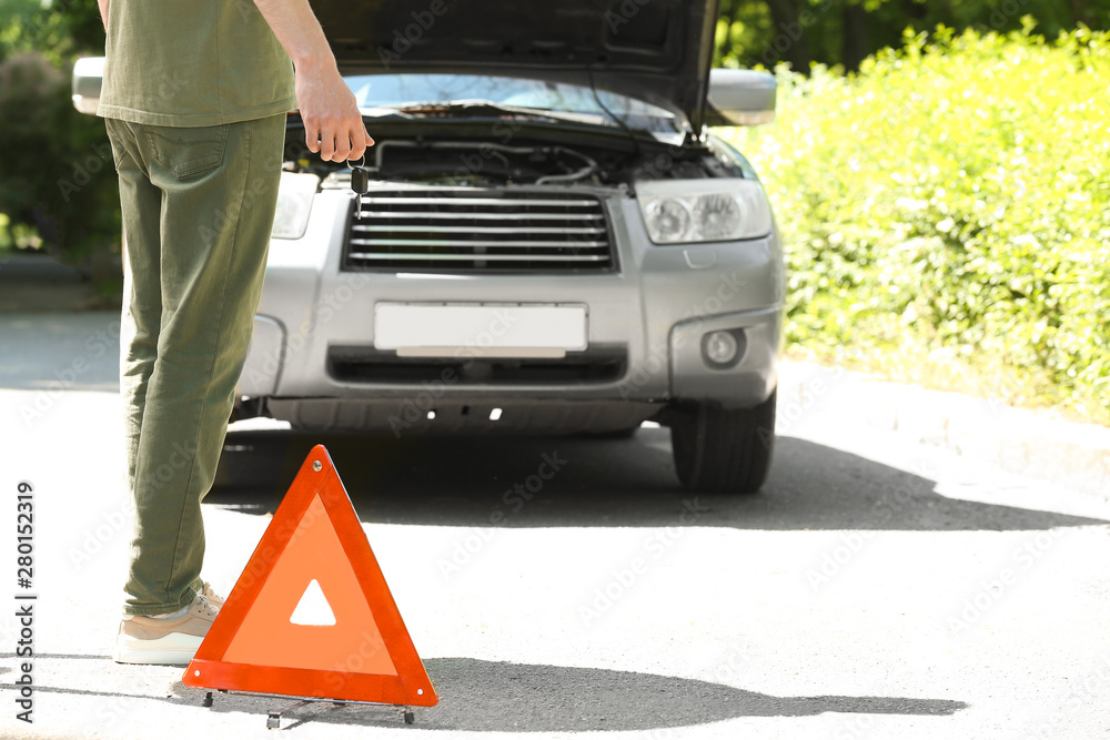 Man near broken car on road