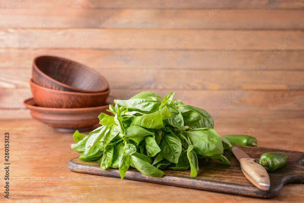 Cutting board with fresh green basil on wooden table