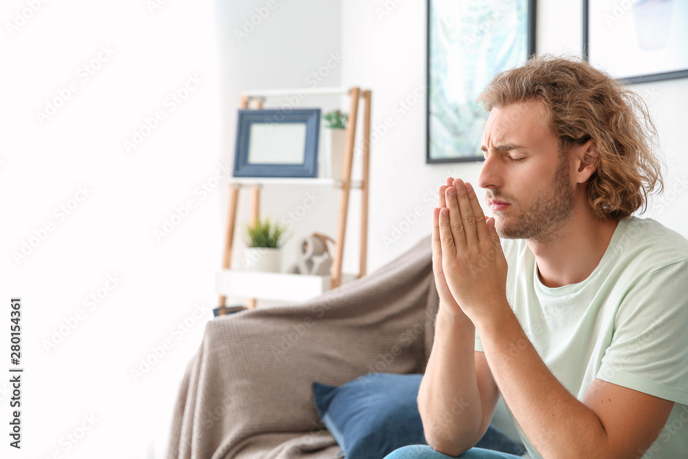 Religious young man praying at home
