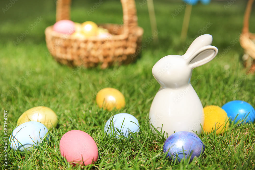 Easter eggs with ceramic bunny on grass outdoors