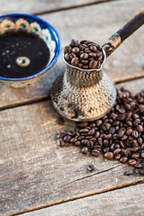 Coffee beans  in a coffeepot or turk on a wooden background