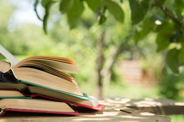 Open book on a wooden table in a garden. Sunny summer day, reading in a vacation concept