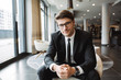 © Drobot Dean - Photo of young businessman wearing eyeglasses sitiing on armchair in hotel lobby
