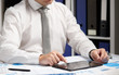 © soleg - Businessman working with tablet pc, calculating, reading and writing reports. Office employee, table closeup. Business financial accounting concept.