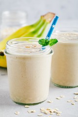 Poster - Banana oats smoothie or milkshake in glass mason jars on a stone background