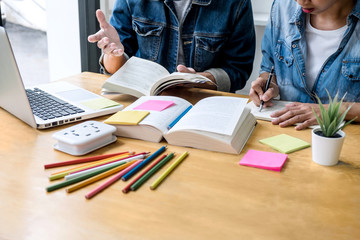 Wall Mural - high school tutor or college student group sitting at desk in library studying and reading, doing ho