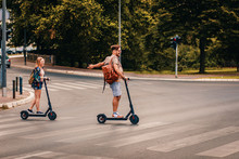 Young Couple On Vacation Having Fun Driving Electric Scooter Through The City.