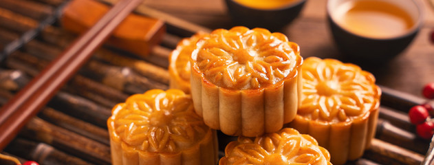 Moon cake Mooncake table setting - Round shaped Chinese traditional pastry with tea cups on wooden background, Mid-Autumn Festival concept, close up.