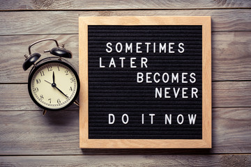 Wall Mural - Inspirational motivational quote Sometimes later becomes never. Do it now words on a letter board on wooden background near vintage alarm clock. Success and motivation concept.
