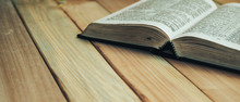Close Up Open Bible Book On A Wooden Table Background.