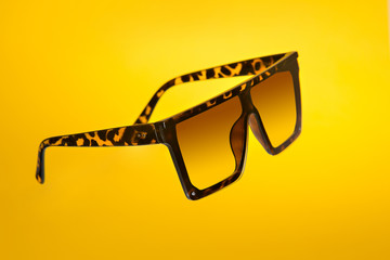 modern sunglasses floating with yellow background, product photography in studio.