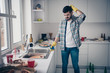 Portrait of his he nice attractive minded annoyed bearded guy wearing checked shirt mess chaos around maid service in modern light white interior style kitchen indoors