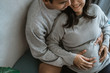 © Odua Images - happiness husband and wife feel pregnancy, sit back together on the couch while holding the belly of a pregnant wife