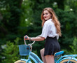 Girl in a skirt with a bike in the park