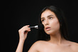 © Tetiana Moish - Beauty woman applying makeup.  Beautiful young  woman applying cosmetic paint brush. Brunette girl apply make-up. Beauty Face. Isolated on black background.