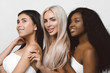 © Tetiana Moish - Beauty photo of three smiling multiracial women with different types of skin: Caucasian, African american and Asian girls, isolated over white background. Beautiful  young women with natural make-up.