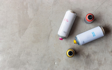 closeup old cans of spray paint on cement floor background. top view and over light