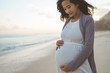 © Odua Images - worried pregnant woman stands on the beach while looking at her stomach