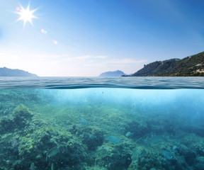 Wall Mural - Blue sunny sky, an island in the ocean and underwater sandy rocky sea view.