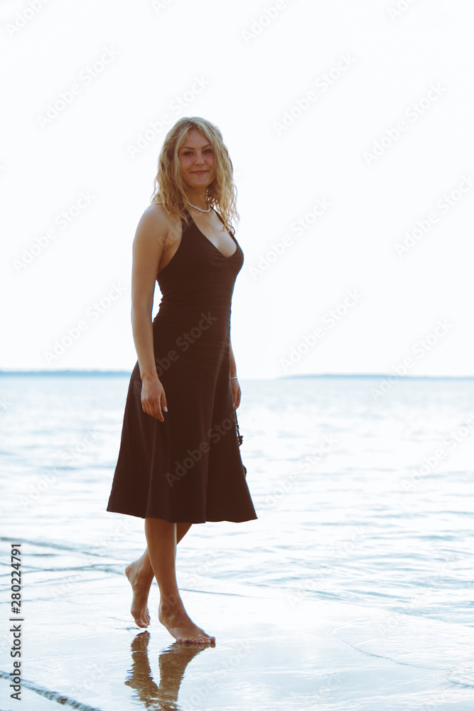 woman in black light dress walking barefoot by sea beach Stock Photo | Adobe Stock woman in black light dress walking barefoot by sea beach Stock Photo | Adobe Stock