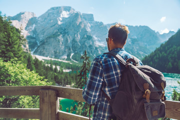man with backpack looking at mountains and lake