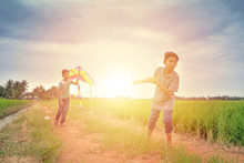 Two Friends Playing With Kite At Paddy Field In The Evening