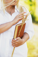 Wall Mural - girl with old book in a white dress shirt in the meadow