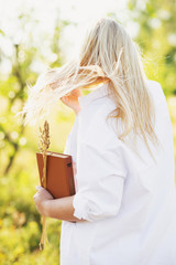 Wall Mural - girl with old book in a white dress shirt in the meadow