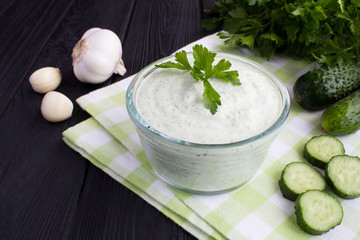 Traditional greek yogurt with cucumber on the black wooden background.Closeup.