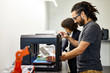 © Cavan Images - Side view of businessman examining model in 3D printer