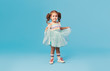© oes - Little happy toddler child girl dreams of becoming ballerina in a cyan tutu skirt. Blue background. Space for text