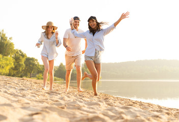 Group of friends having fun running down the beach