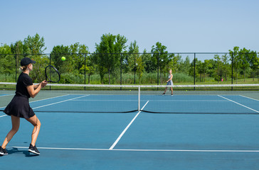 Young sports women playing tennis on the blue tennis court