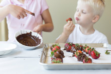 A Little Boy And Girl Making And Eating Chocolate And Strawberries
