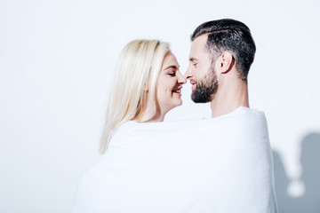 smiling girlfriend and boyfriend covered in blanket on white