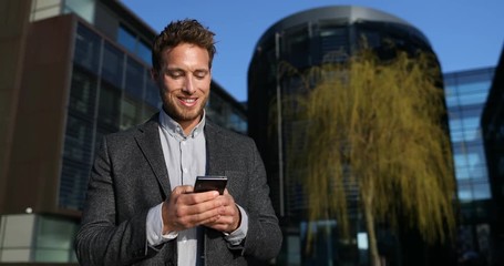 Wall Mural - Phone - young businessman using smartphone in smart casual suit by office in city. Urban business man professional outside using mobile phone app outdoors confident in blazer. 59.94 FPS