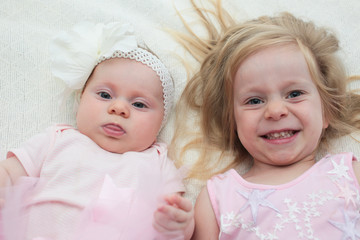 Two Sisters, One Cute 3 Years Old Toddler Girl and 4 Month Old Cute Baby Girl, Infant, Playing on the white bed, New family concept, The most Beautiful Girls Princesses 