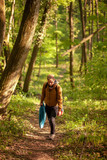 Fototapeta Nowy Jork - One young man, in forest alone, trekking, walking. Carrying camp