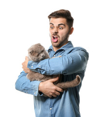 Wall Mural - Grimacing young man with cute funny cat on white background