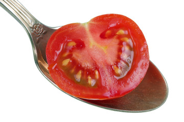 Wall Mural - In the old golden spoon there is a small piece of food - half a ripe cherry tomato isolated macro