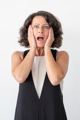 Wall Mural - Scared woman looking at camera. Front view of shocked middle aged woman standing with open mouth isolated on grey background. Emotion concept