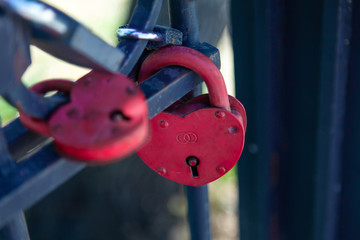 Close-up on locks of hearts in different colors and shapes hanging on the fence as a sign of eternal love, which is hung during the wedding.